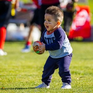 A small child playing football hopefully avoiding any childhood tooth injuries