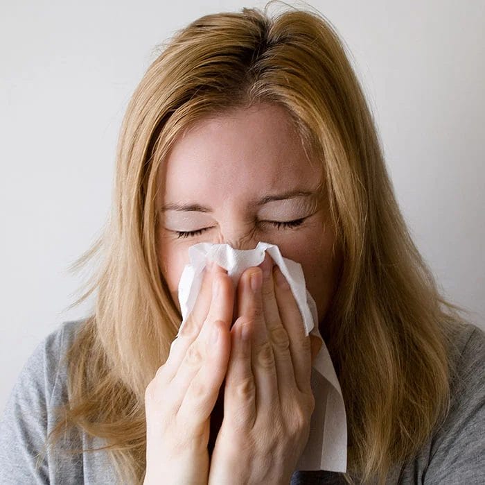 Woman with a cold blowing her nose