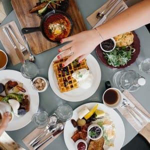 Hand reaching in to grab food from a table filled with different food dishes.