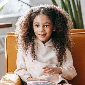 A small girl sitting on a chair with a book
