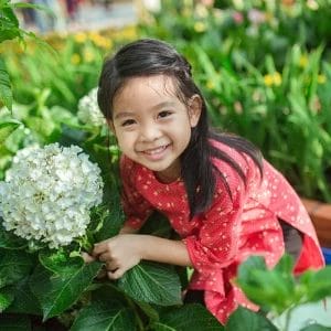 Young girl smiling while holding a large white flower