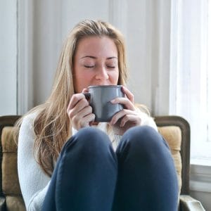 Woman drinking a hot beverage that may cause some sensitive teeth
