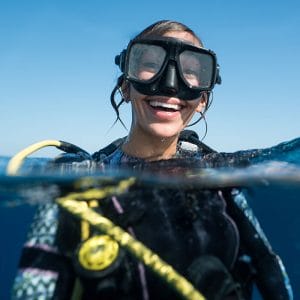 Woman smiling while scuba diving which is one of 2 dental issues during summer